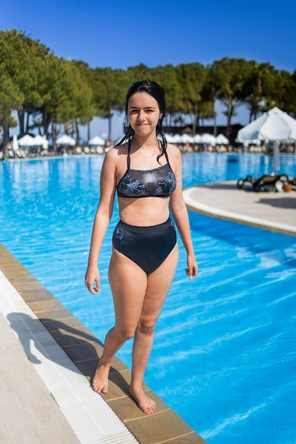 Jovem morena posando em uma piscina azul em um hotel na Turquia