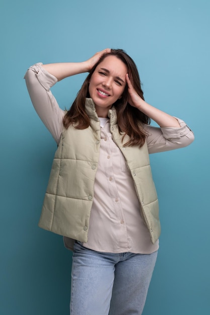 Jovem morena segurando a cabeça dela e posando no fundo do estúdio