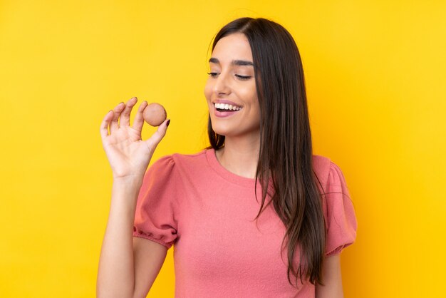 Foto jovem morena segurando macarons franceses coloridos