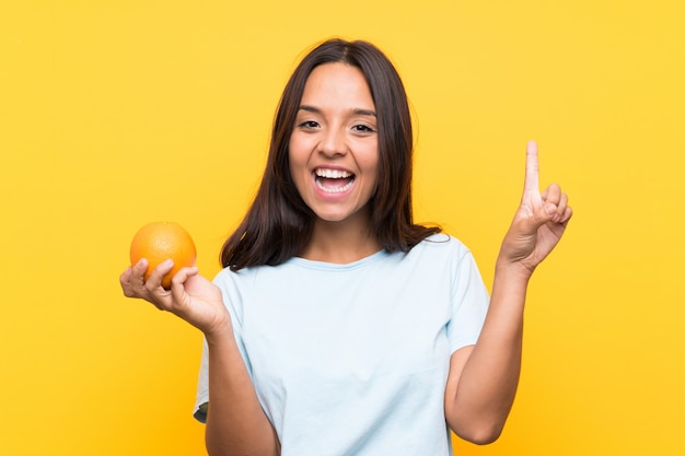 Jovem morena segurando uma laranja apontando uma ótima idéia