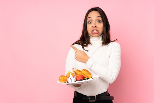 Jovem morena segurando waffles isolados