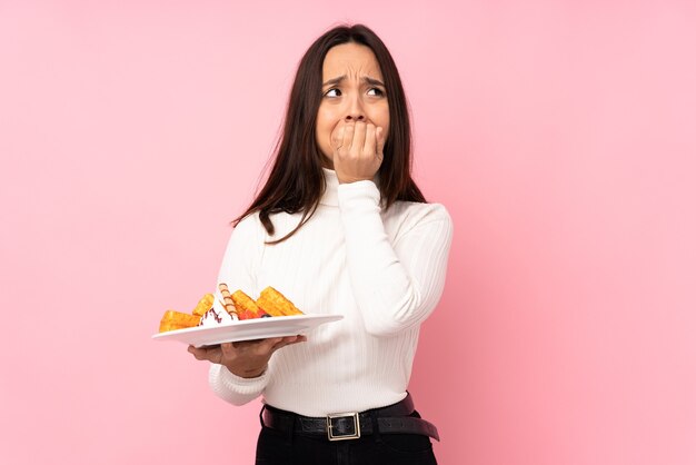 Jovem morena segurando waffles isolados