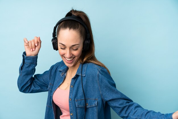 Foto jovem morena sobre música azul isolada parede e dançar