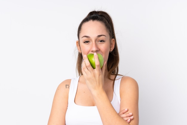 Foto jovem morena sobre parede branca isolada, comendo uma maçã