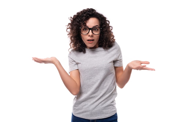 Foto jovem morena sorridente mulher encaracolada vestida com uma camiseta de cor corporativa básica cinza com maquete de impressão