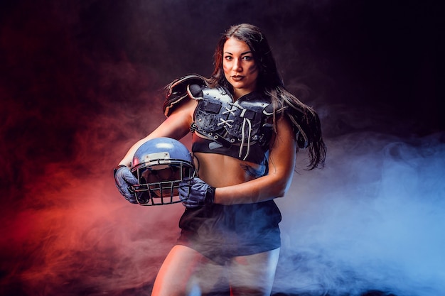 Jovem morena vestindo uniforme de jogador de futebol de rugby posando.