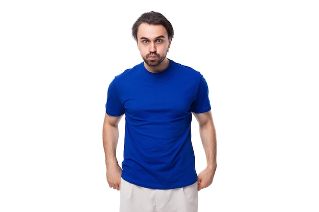 Jovem moreno bem arrumado com barba vestido com uma camisa azul entre um fundo branco