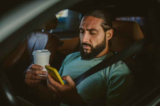 Jovem moreno bonito segurando um telefone e dirigindo um carro