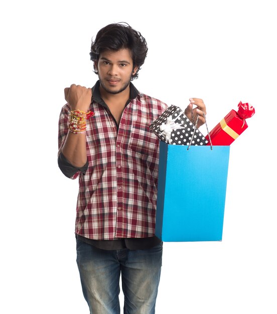 Foto jovem mostrando rakhi na mão com sacolas de compras e caixa de presente por ocasião do festival raksha bandhan.