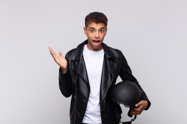 Jovem motociclista sentindo-se feliz, surpreso e alegre, sorrindo com atitude positiva, percebendo uma solução ou ideia