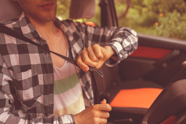 Jovem motorista do sexo masculino apertando o cinto de segurança do carro