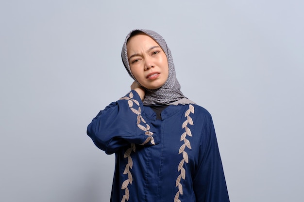 Jovem muçulmana asiática tocando seu pescoço sentindo-se cansada após longas horas de trabalho isoladas sobre fundo branco