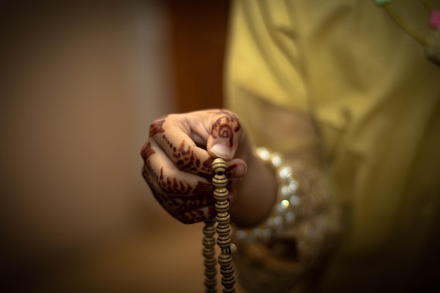 Jovem muçulmana rezando com batidas de oração e design mehndi nas mãos com espaço para texto