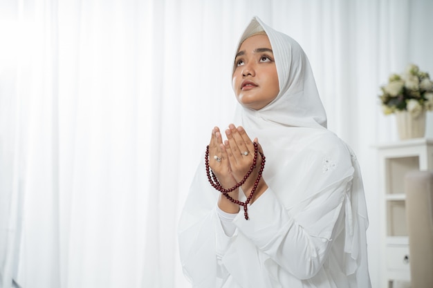 Jovem muçulmana rezando em roupas brancas tradicionais