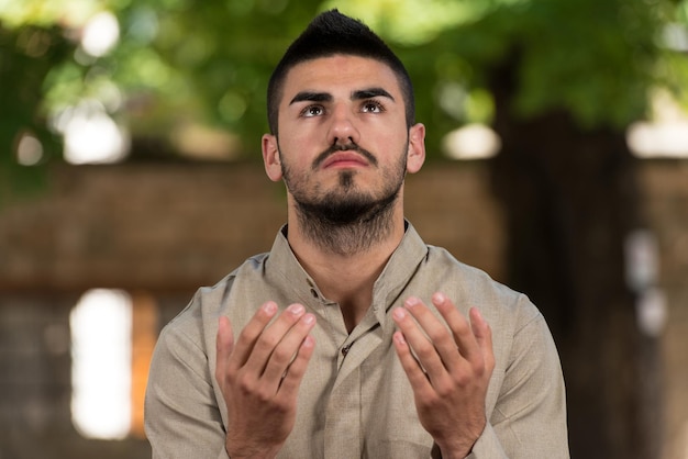 Jovem muçulmano fazendo oração tradicional a Deus enquanto usava um boné tradicional Dishdasha