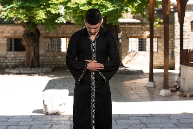 Jovem muçulmano fazendo oração tradicional a Deus enquanto usava um boné tradicional Dishdasha