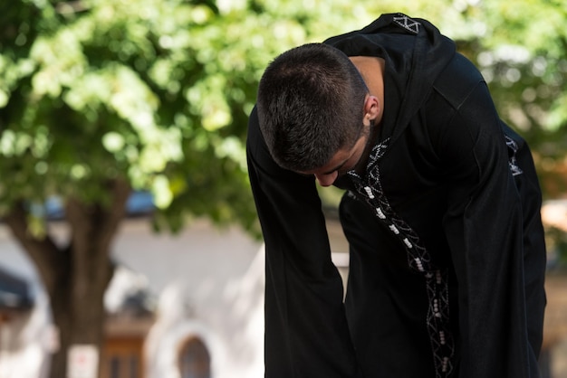 Jovem muçulmano fazendo oração tradicional a deus enquanto usava um boné tradicional dishdasha