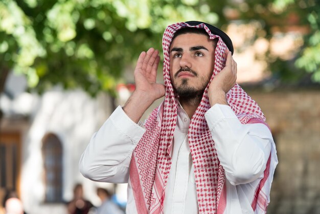 Jovem muçulmano fazendo oração tradicional a Deus enquanto usava um boné tradicional Dishdasha