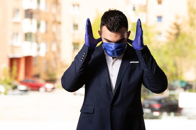 Jovem muçulmano rezando ao ar livre usando luvas e máscara protetora