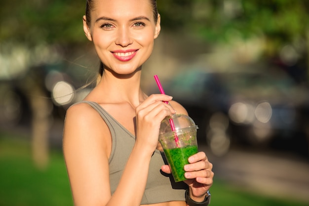 Jovem mulher a beber smoothie de desintoxicação saudável ao ar livre