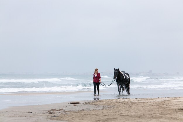 Jovem mulher a cavalo na praia