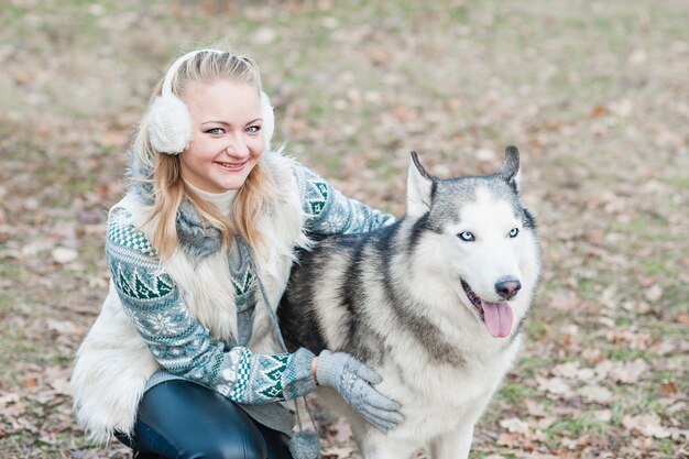 Jovem mulher abraçando seu cão husky