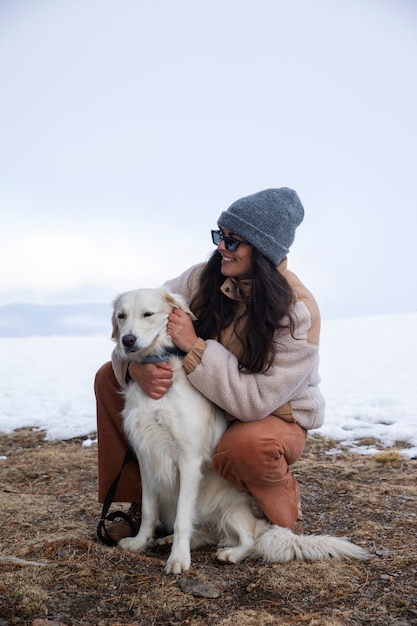 Jovem mulher acariciando seu labrador durante a viagem de inverno