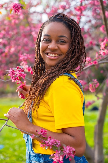 Jovem mulher africana ao lado de uma árvore floral rosa