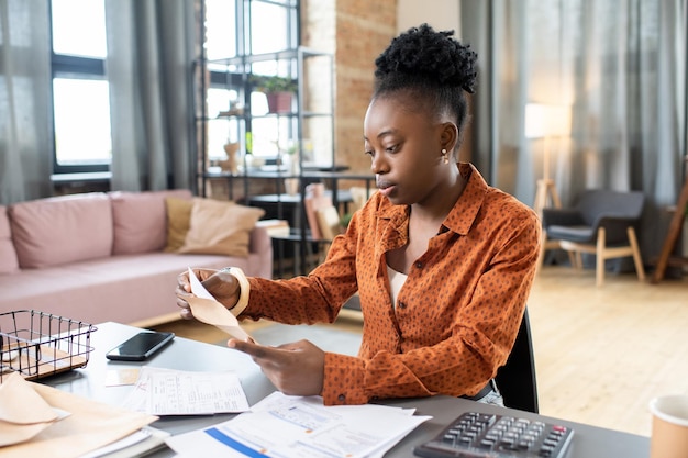 Jovem mulher africana colocando formulário preenchido em envelope