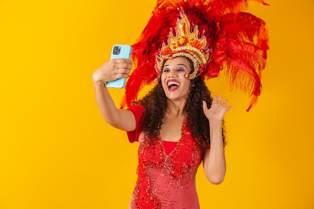 Jovem mulher africana com roupa de samba no carnaval, apreciando a distância no celular.