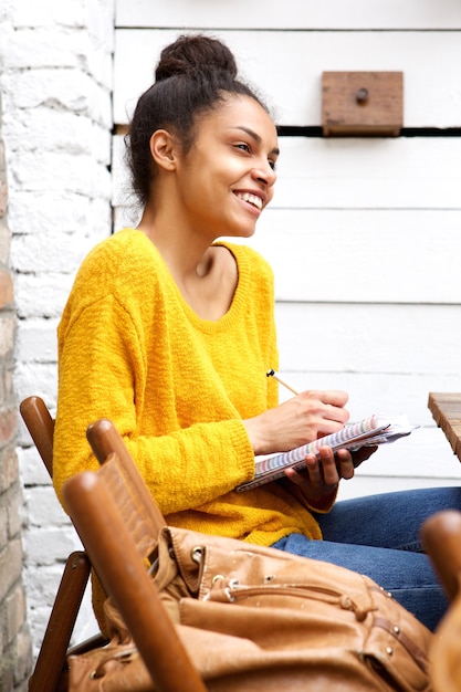 Jovem mulher africana escrevendo no livro no café