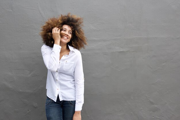 Jovem mulher africana rindo com a mão no cabelo