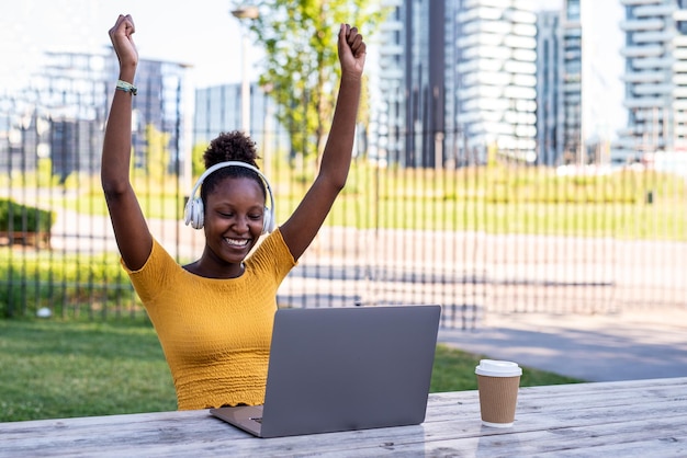 Jovem mulher africana usando laptop ao ar livre alegria e felicidade para ganhar o resultado