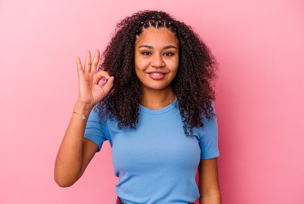 Jovem mulher afro-americana, alegre e confiante, mostrando um gesto ok.