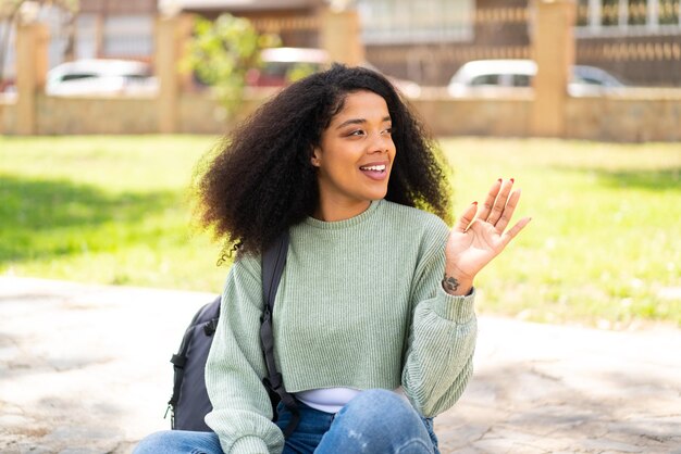 Jovem mulher afro-americana ao ar livre cumprimentando