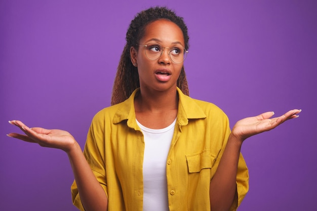 Jovem mulher afro-americana casual confusa espalha os braços para o lado