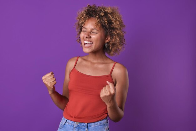 Foto jovem mulher afro-americana, cheia de alegria, agita os braços com entusiasmo e grita: