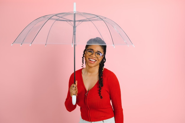 Jovem mulher afro-americana com cabelo afro sob o guarda-chuva.