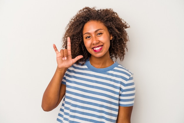 Jovem mulher afro-americana com cabelo encaracolado, isolado no fundo branco, mostrando um gesto de chifres como um conceito de revolução.