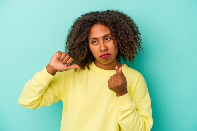 Jovem mulher afro-americana com cabelos cacheados, isolado em um fundo azul, mostrando que ela não tem dinheiro.