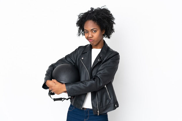 Jovem mulher afro-americana com um capacete de moto isolado na parede branca, pensando em uma idéia