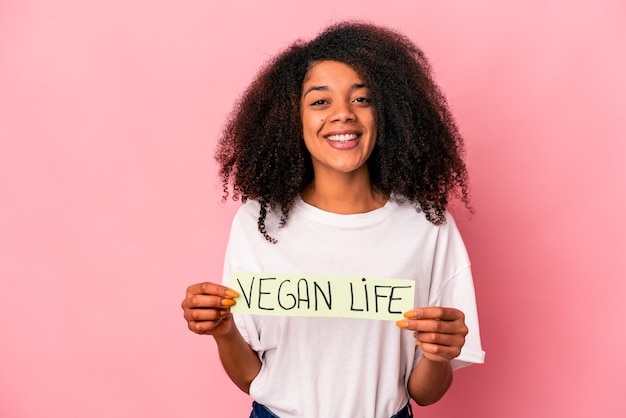 Jovem mulher afro-americana encaracolada segurando um cartaz de vida vegana feliz, sorridente e alegre.