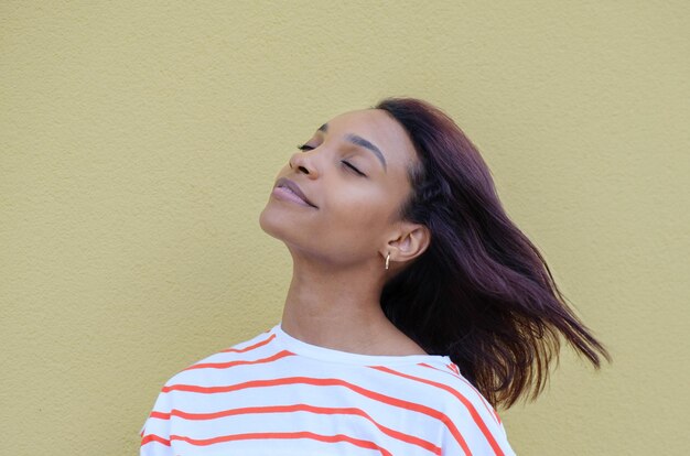 Foto jovem mulher afro-americana espiritual de 20 anos vestindo blusa branca casual relaxando meditando tentando se acalmar isolado no fundo amarelo conceito de estilo de vida de pessoas