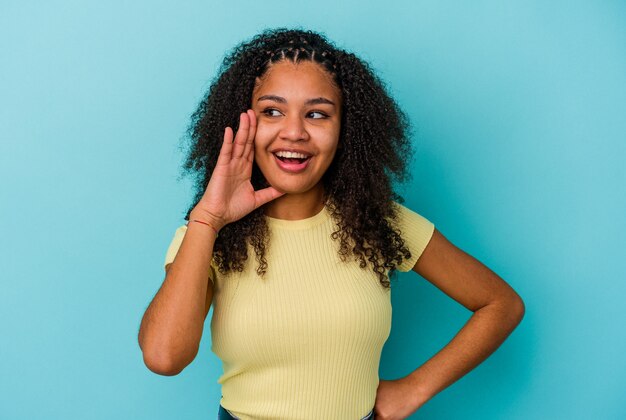 Jovem mulher afro-americana gritando animado para a frente.