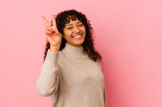 Jovem mulher afro-americana isolada alegre e despreocupada, mostrando um símbolo de paz com os dedos.