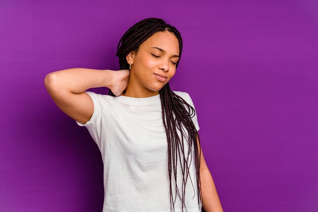 Jovem mulher afro-americana isolada em amarelo tendo uma dor de garganta devido ao estresse, massageando e tocando com a mão.