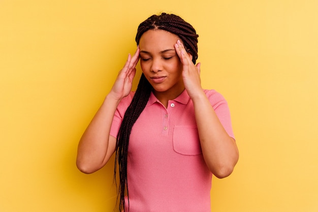 Jovem mulher afro-americana isolada em amarelo tocando as têmporas e tendo dor de cabeça.