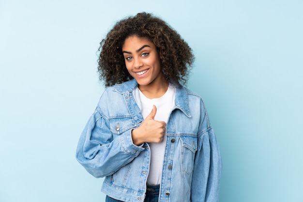 Jovem mulher afro-americana isolada em azul, dando um polegar para cima gesto