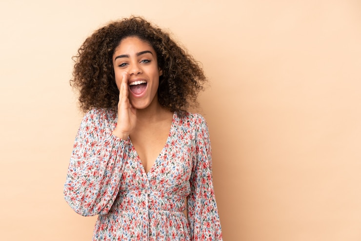 Foto jovem mulher afro-americana isolada em bege, gritando com a boca aberta
