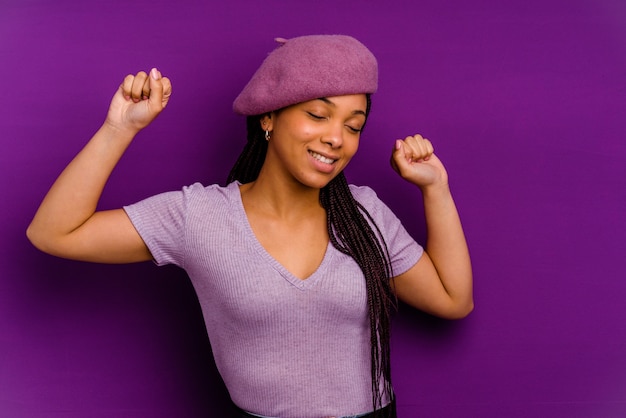 Jovem mulher afro-americana isolada em fundo amarelo Jovem mulher afro-americana isolada em fundo amarelo, comemorando um dia especial, pula e levanta os braços com energia.